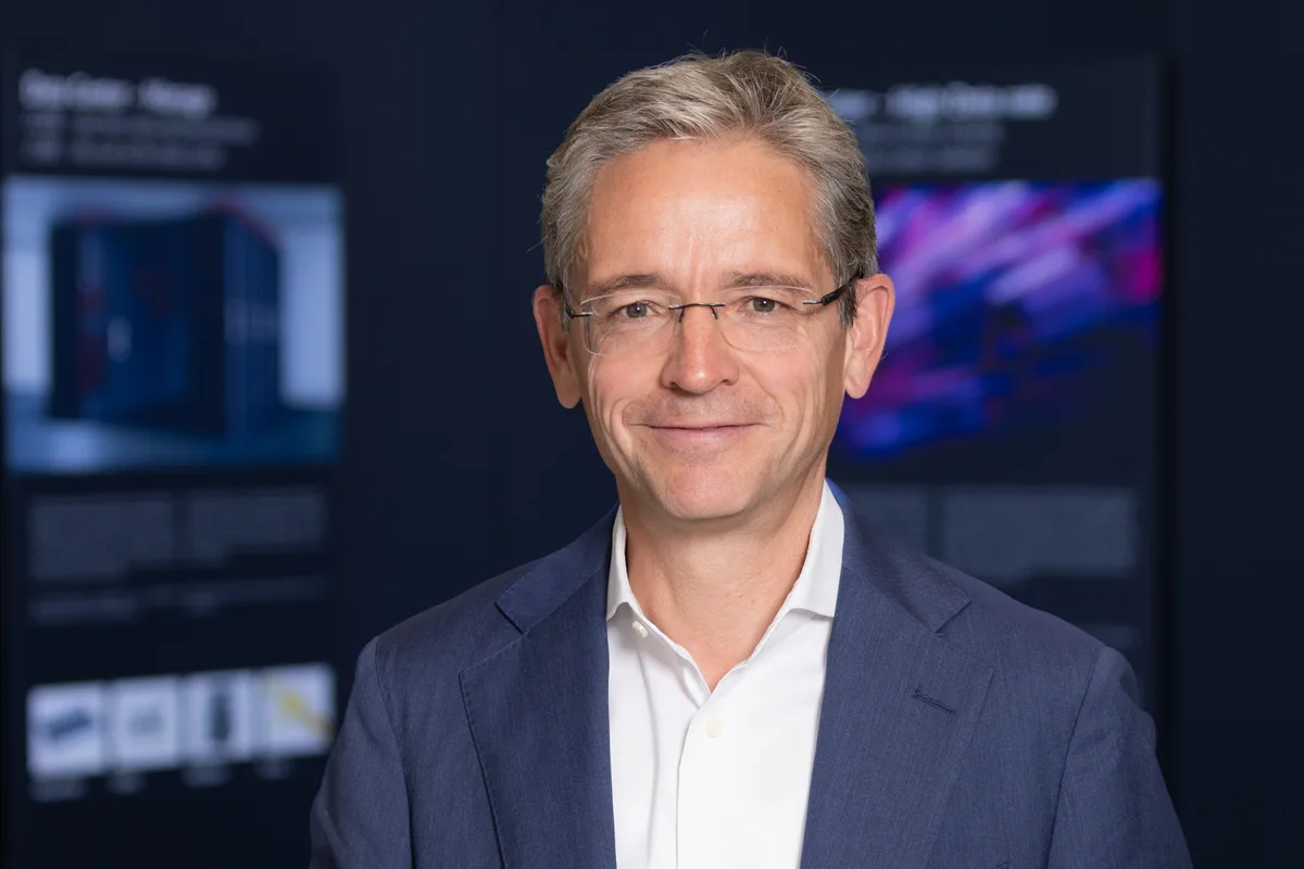 Roger Baumann verfügt über Management-, Technologie- und Vertriebserfahrung in der produzierenden Industrie. Porträtbild von Roger Baumann. Ein Mann mit Brille, blauem Anzug und offenem weissem Hemd.